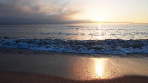 Black Sea and Beach Nearby Against a Sky with Clouds and a Dawn Sun
