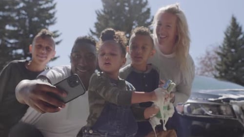 Cheerful multiethnic family takes a selfie together near a carwash in Canada