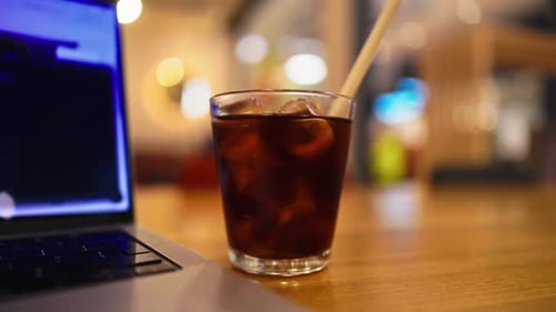 Savoring a Chilled Iced Coffee Drink Placed Next to My Laptop in a Cozy and Inviting Cafe