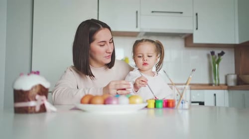 Happy Easter Holiday. Beautiful mother and daughter paint and decorate an egg.