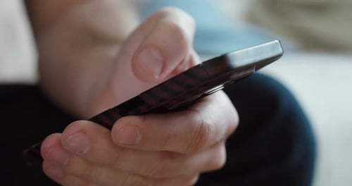 Man Holding Smartphone Close Up While Sitting
