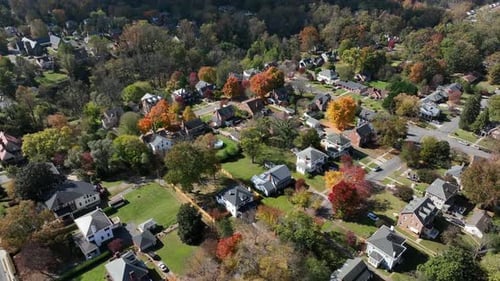 Quiet residential area of america with large houses and orange colored trees in fall season. Aerial