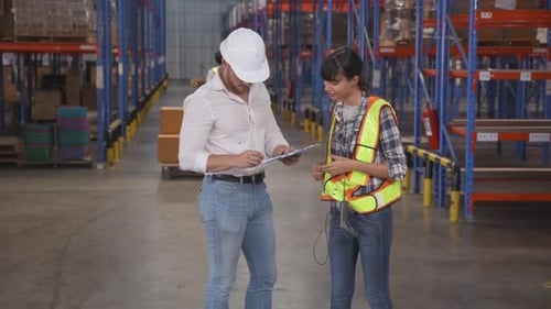 Young woman talking with manager while signature document on clipboard in the warehouse at factory.