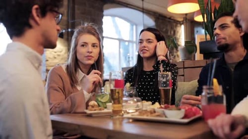 Happy young multiethnic friends enjoying food and drinks at a cafe bar