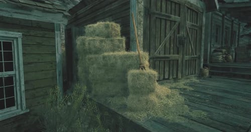 Stacked Hay Bales Near Wooden Building in Rural Countryside at Dusk
