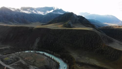 Sunlight Illuminating a Mountain Valley Reveals a Turquoise River Winding Through the Landscape