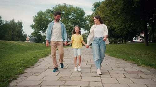 Happy Parents and Daughter Smile Walking Joining Hands in Park