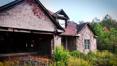 Abandoned brick house surrounded by woods during fall mid day