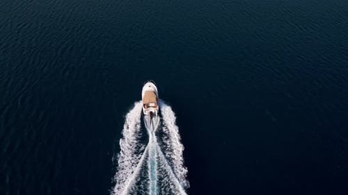 Aerial Video of a Motorboat Cruising Through Deep Blue Sea Leaving a Foamy Wake Dynamic and Scenic