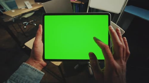 Close Up Hands Man Holding Scrolling a Tablet Computer with a Horizontal Green Screen in Office