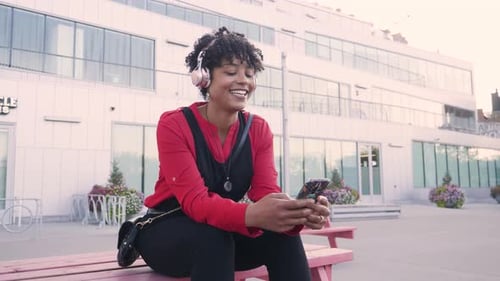 Smiling Woman Listens to Music on Bench