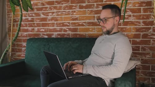 Man Working on Laptop at Home on Couch