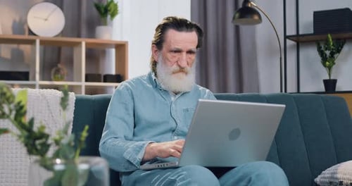 Senior Man Using Laptop on Couch at Home