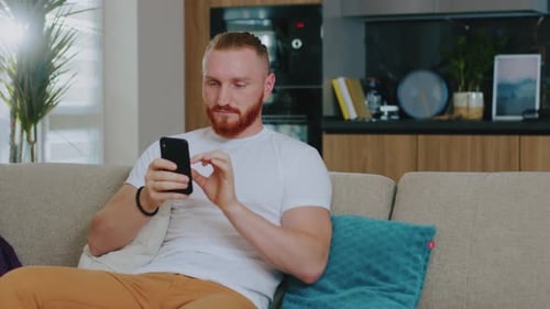 Man Relaxing on Couch Using Smartphone