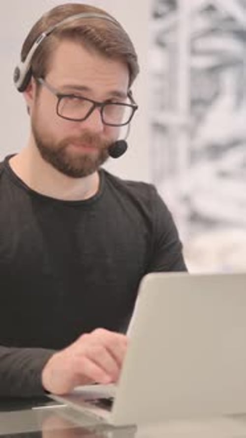 Adult Man with Headset Looking toward Camera in Call Center, vertical