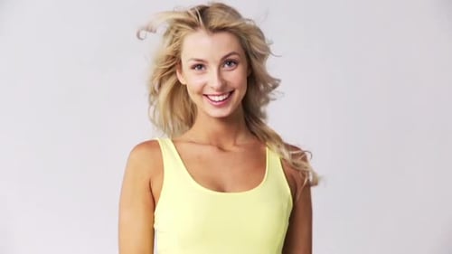 Happy blonde woman smiles and winks in studio