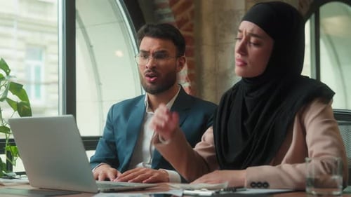 Business colleagues discuss issues on laptop in office