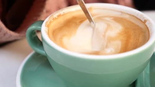 Silver Spoon Stirring Delicious Latte in Green Cup