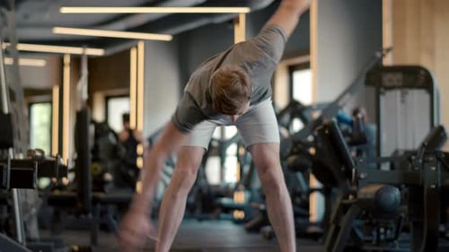Handsome Fitness Man Making Hand Swings at Gym. Serious Sportsman Doing Crossfit