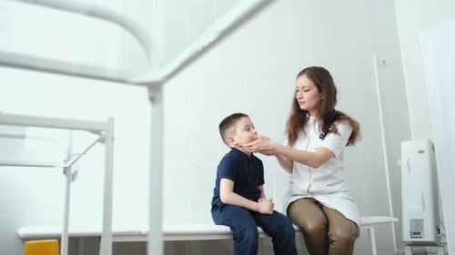 pediatrician examines a boy sitting on a couch in a treatment room