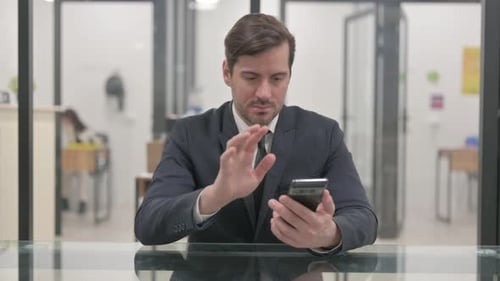 Man in Suit Using Cell Phone at Desk