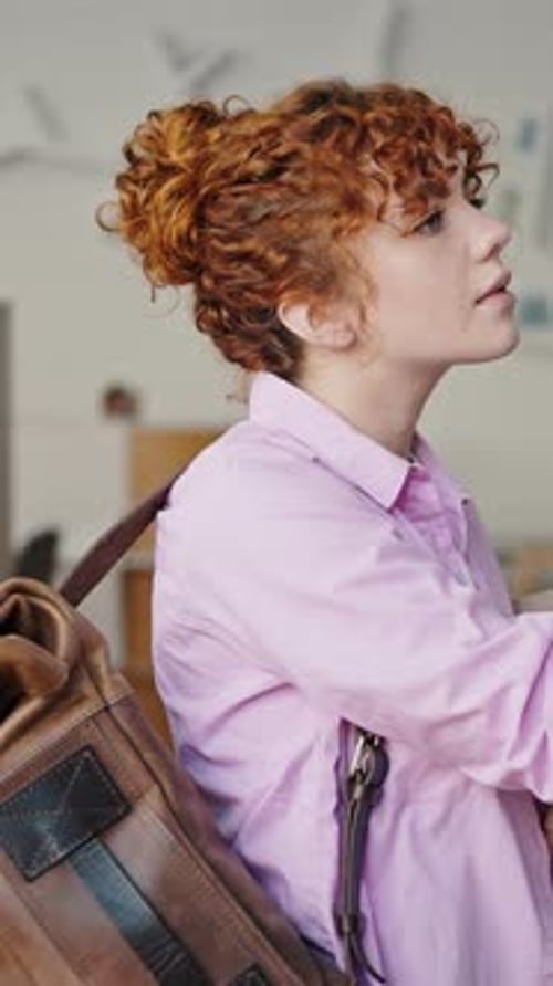Woman Reads Book Near Bookshelf in Library