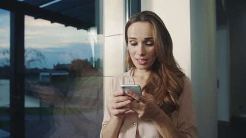 Woman Smiling Using Smartphone Inside Modern Home