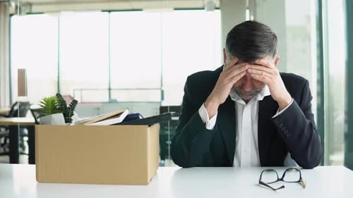 Senior Employee Sitting with Dismissal Box