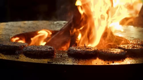 Saftige, saftige Rindfleischpastetchen werden während eines Barbecues auf einem hausgemachten Grill über offener Flamme zubereitet