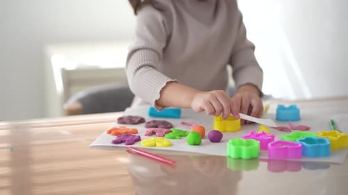 Young Child Plays With Colorful Modelling Clay at Table