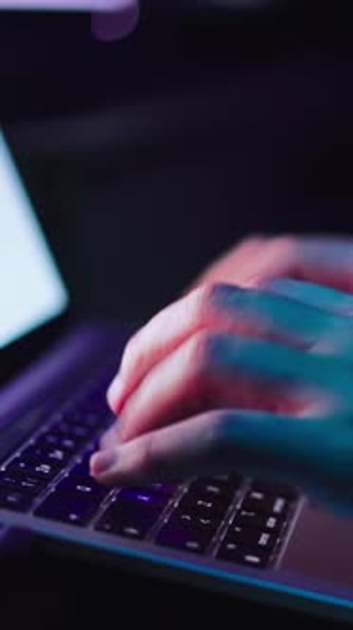 Gros plan latéral méconnaissable, mains d'un jeune homme tapant sur le clavier d'un ordinateur portable dans le système de sécurité de la chambre noire