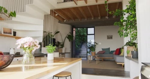 General view of modern kitchen and living room with countertop, sofa and staircase