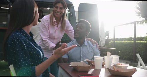Amigos multirraciales que comen en la mesa de un camión de comida al aire libre: verano y estilo de vida