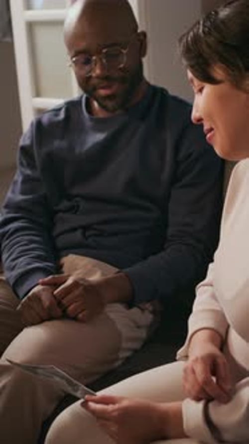 Un homme pose des questions à sa femme enceinte sur la photo échographique de leur bébé