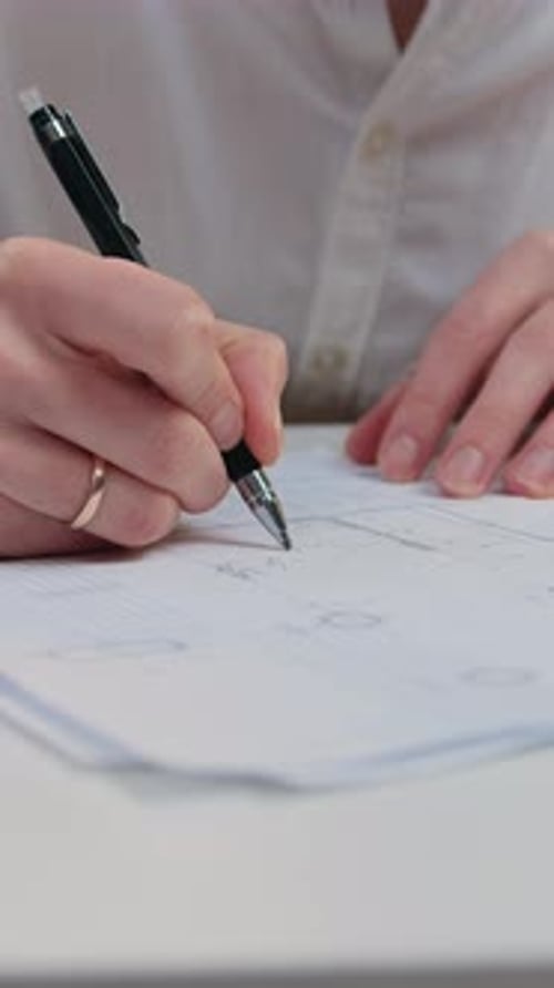Nahaufnahme eines Mannes in modischer Kleidung, der am Küchentisch sitzt und mit wichtigen Dokumenten arbeitet