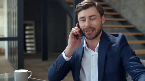Happy businessman talking on phone looking at diagrams in modern office slow motion
