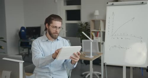 Bearded Man Working on a Tablet in Office