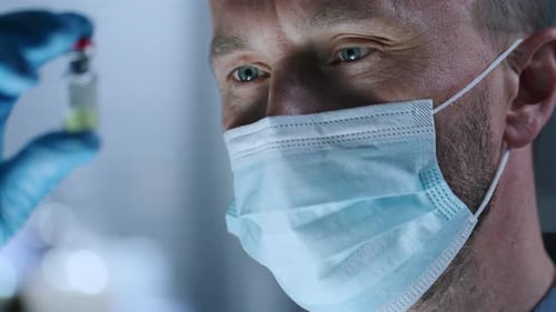 Healthcare Worker Examining Vial of Medicine