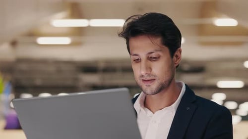 Young IT Worker Writing Code Using the Laptop While Sitting in the Lounge Zone