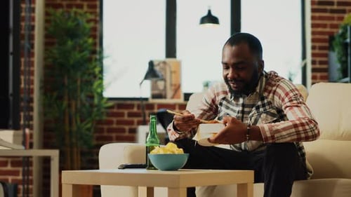 Man Relaxes on Sofa and Enjoys a Takeout Meal