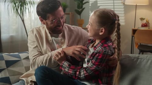 Happy Father and Daughter Playfully Interact on Sofa