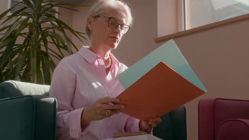 Confident Businesswoman Reviewing Documents in Sunlit Office