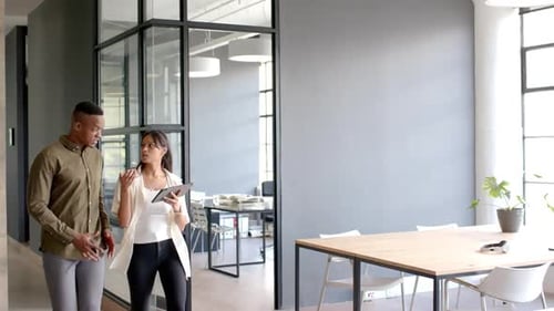 Discussing business strategy, colleagues walking in modern office holding tablet