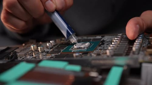 Closeup of Technician Male Applying Thermal Paste to Computer Processor Chip on Motherboard to