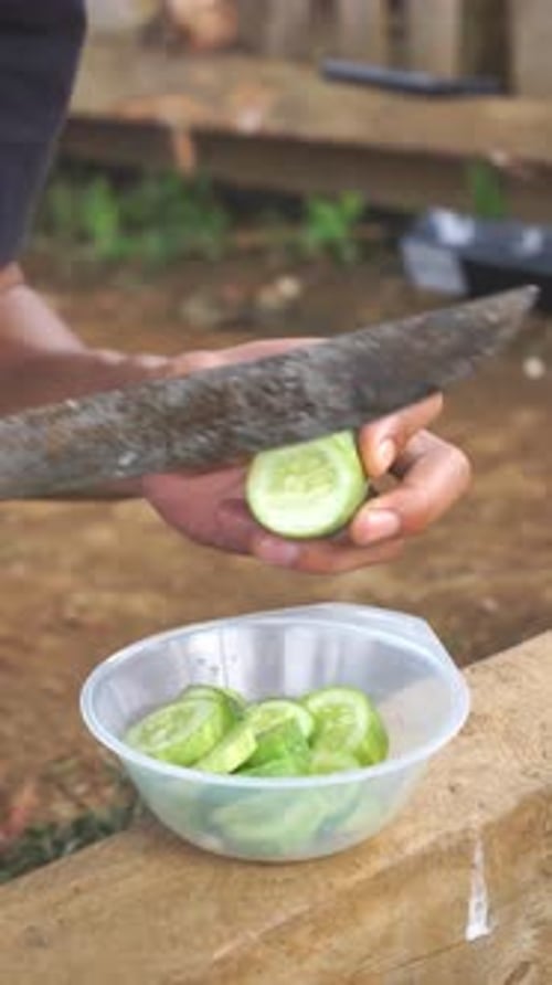Slicing Fresh Cucumbers with Rustic Knife Outdoors