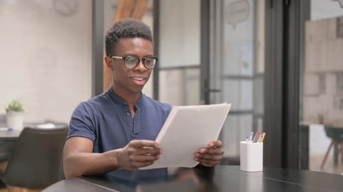 Young Man Excitedly Reading Documents in Office