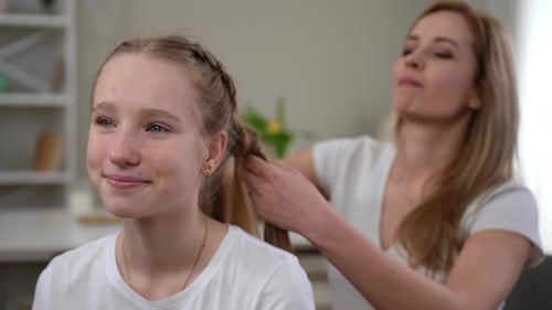 A Mother Styles Her Daughters Hair in a Cozy Home Filled with Warmth and Affection