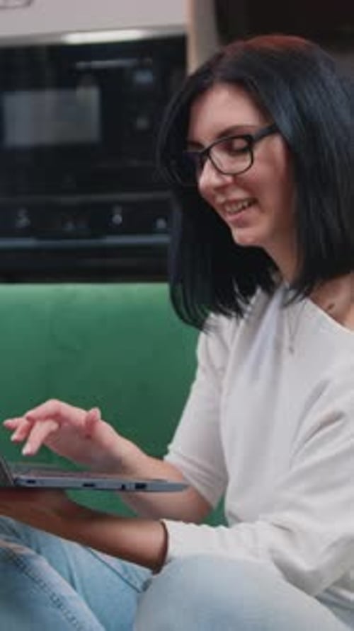 Smiling Woman Uses Laptop on Sofa Indoors