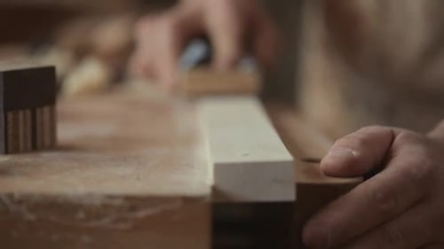 Craftsman Smoothing Wood with Sandpaper on Workbench