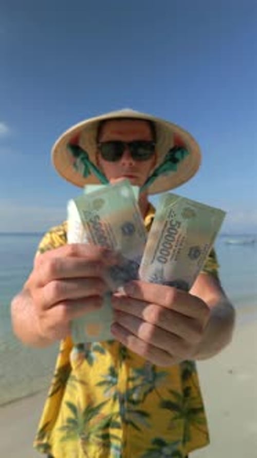 Man Counting Vietnamese Dong on the Tropical Beach in Vietnam
